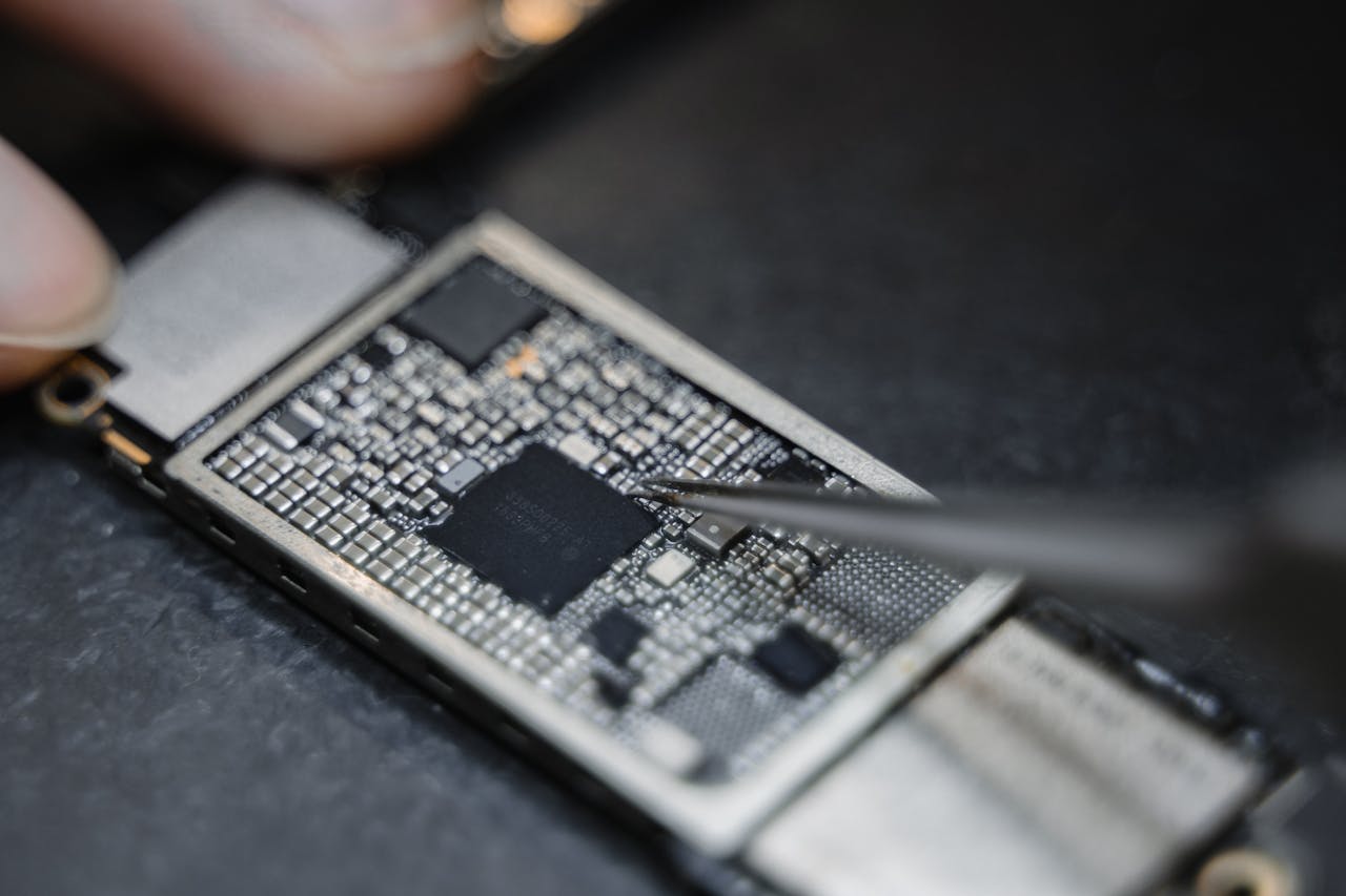 get-in-touch Detailed view of a technician using tweezers to fix an electronic circuit board.